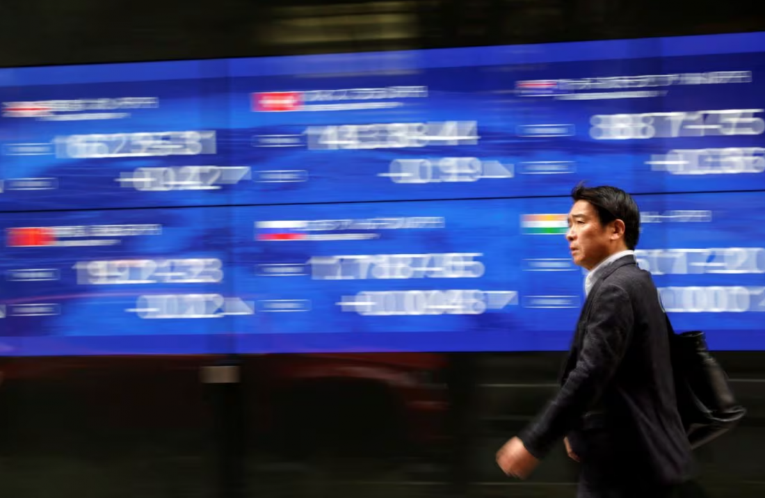 Một người qua đường đi ngang qua màn hình điện hiển thị chỉ số giá cổ phiếu của nhiều quốc gia khác nhau bên ngoài một ngân hàng ở Tokyo, Nhật Bản, ngày 22 tháng 3 năm 2023. REUTERS/Issei Kato